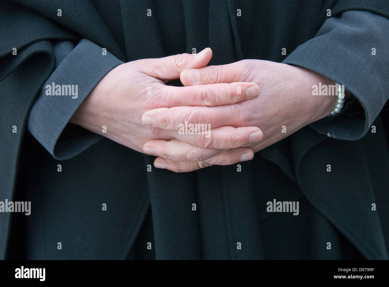Una femmina di funerale leader è pieghevole rispettosamente le mani Foto Stock