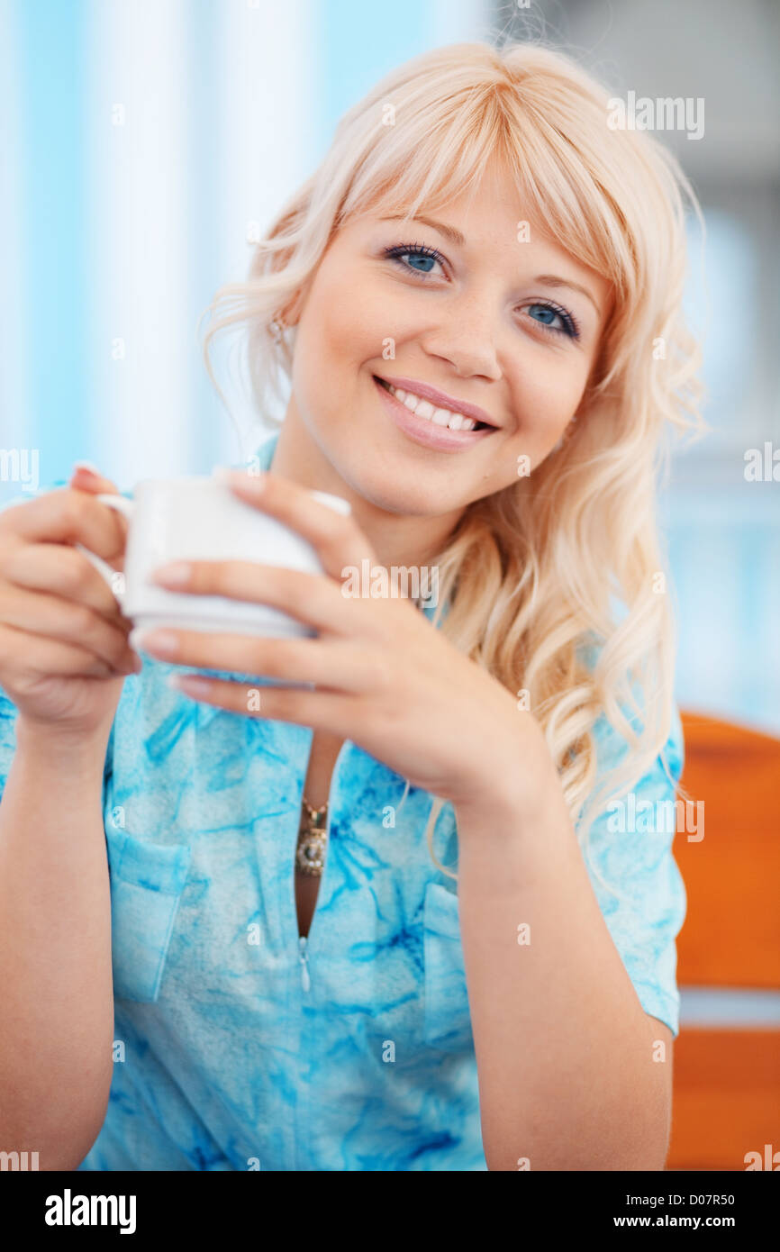 Luminose ritratto della bella ragazza sorridente con la tazza di tè in cafe Foto Stock