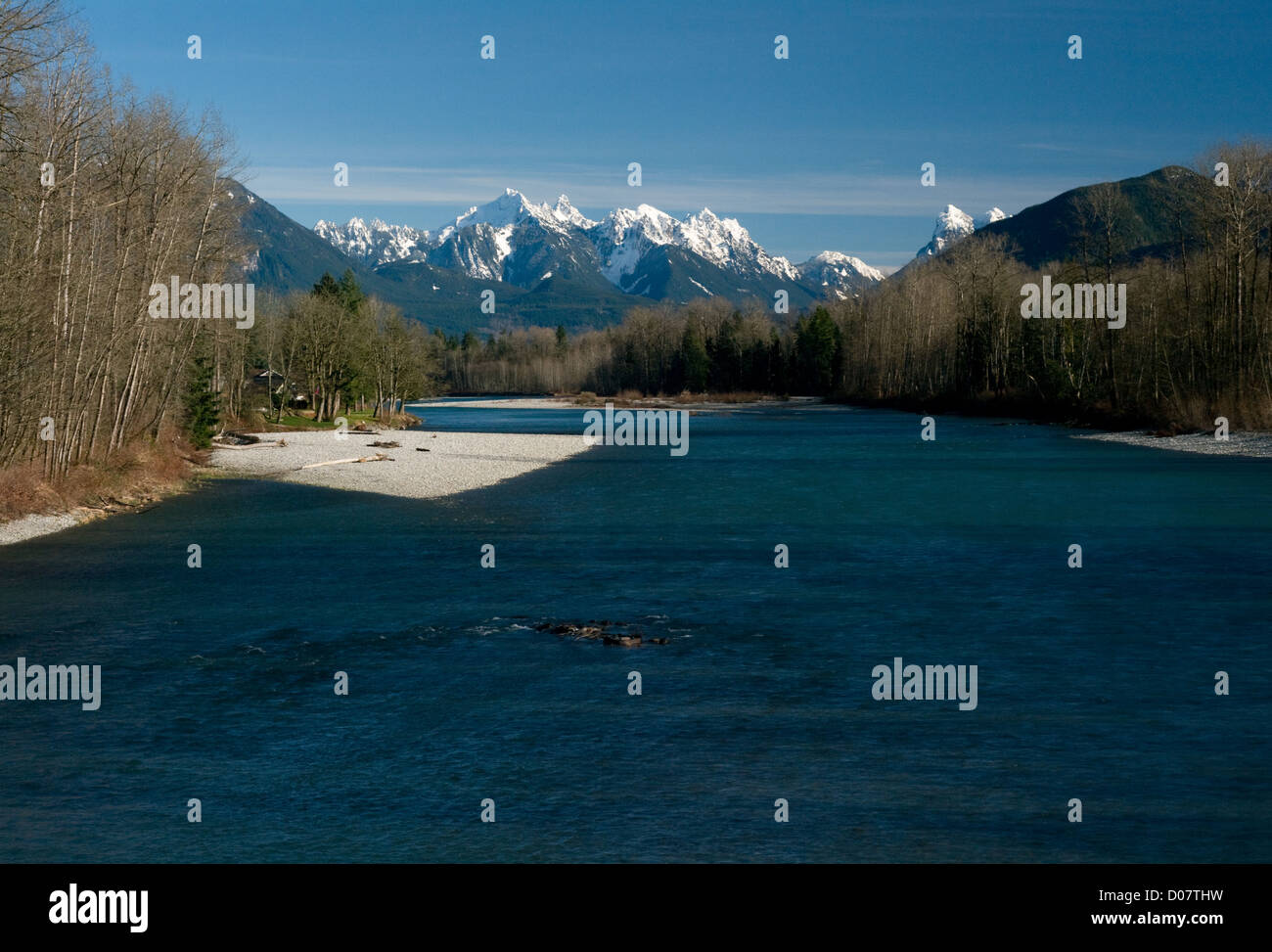 La snow-capped Cascade Mountains salire maestosamente sopra il fiume Skokomish vicino a Sultan, Washington, Stati Uniti d'America. Foto Stock