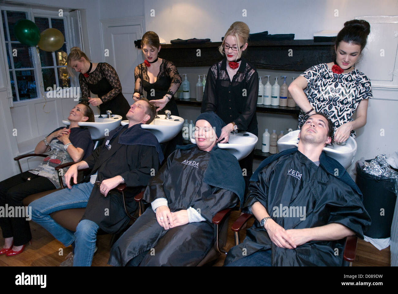 I clienti di un parrucchiere avente capelli lavati prima di avere il loro taglio di capelli, Farnham, Surrey, Regno Unito. Foto Stock