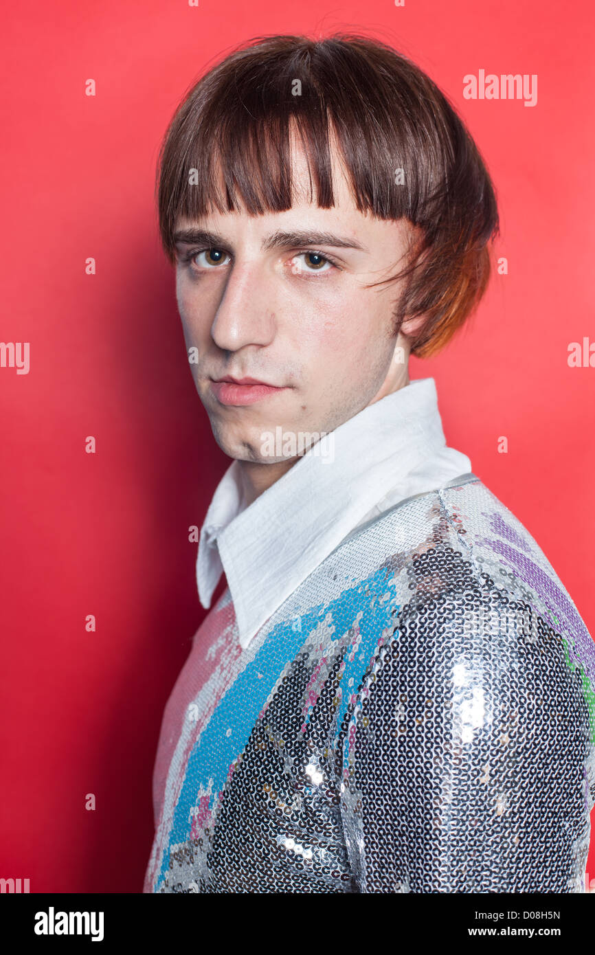 Giovane uomo su sfondo rosso vestito di paillettes disco metallico shirt Foto Stock