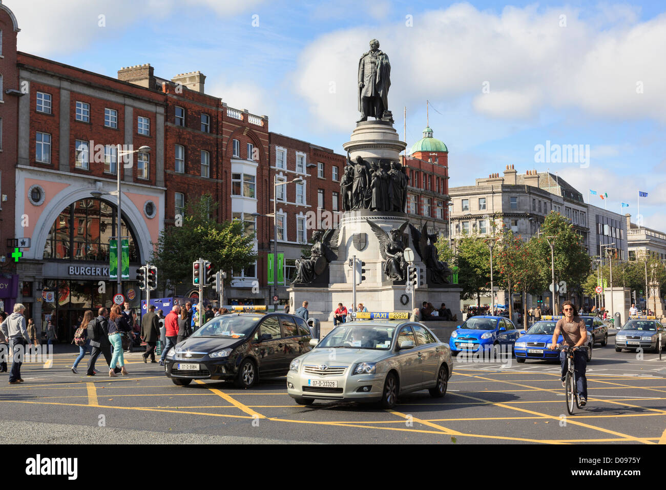 Strada trafficata scena con il traffico della città il passaggio di Daniel O'Connell monumento su O'Connell Street, Dublin, Irlanda meridionale, Eire Foto Stock