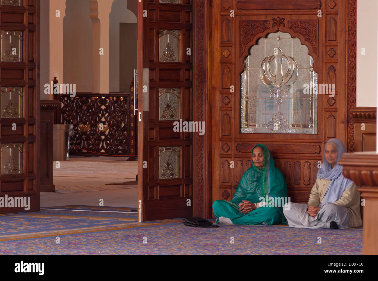 Due anziani asiatici indiano sikh seduto sul pavimento in un Darbar Sahib di un Gurdwara Sikh con le mani in preghiera Foto Stock