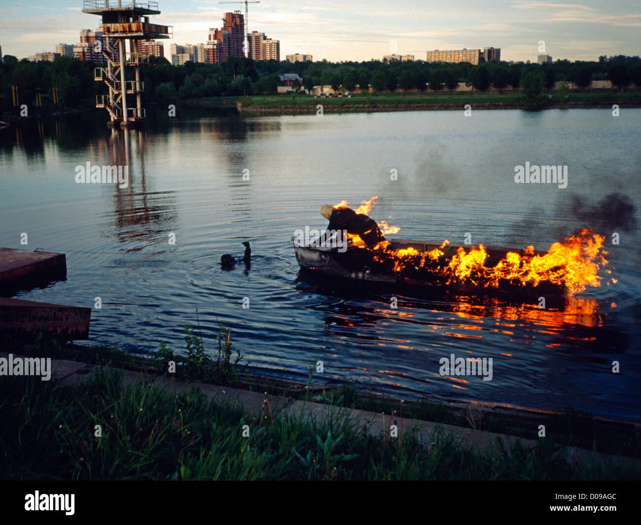 Film stunt di barca sul fuoco con stuntman e subacqueo di sicurezza Foto Stock