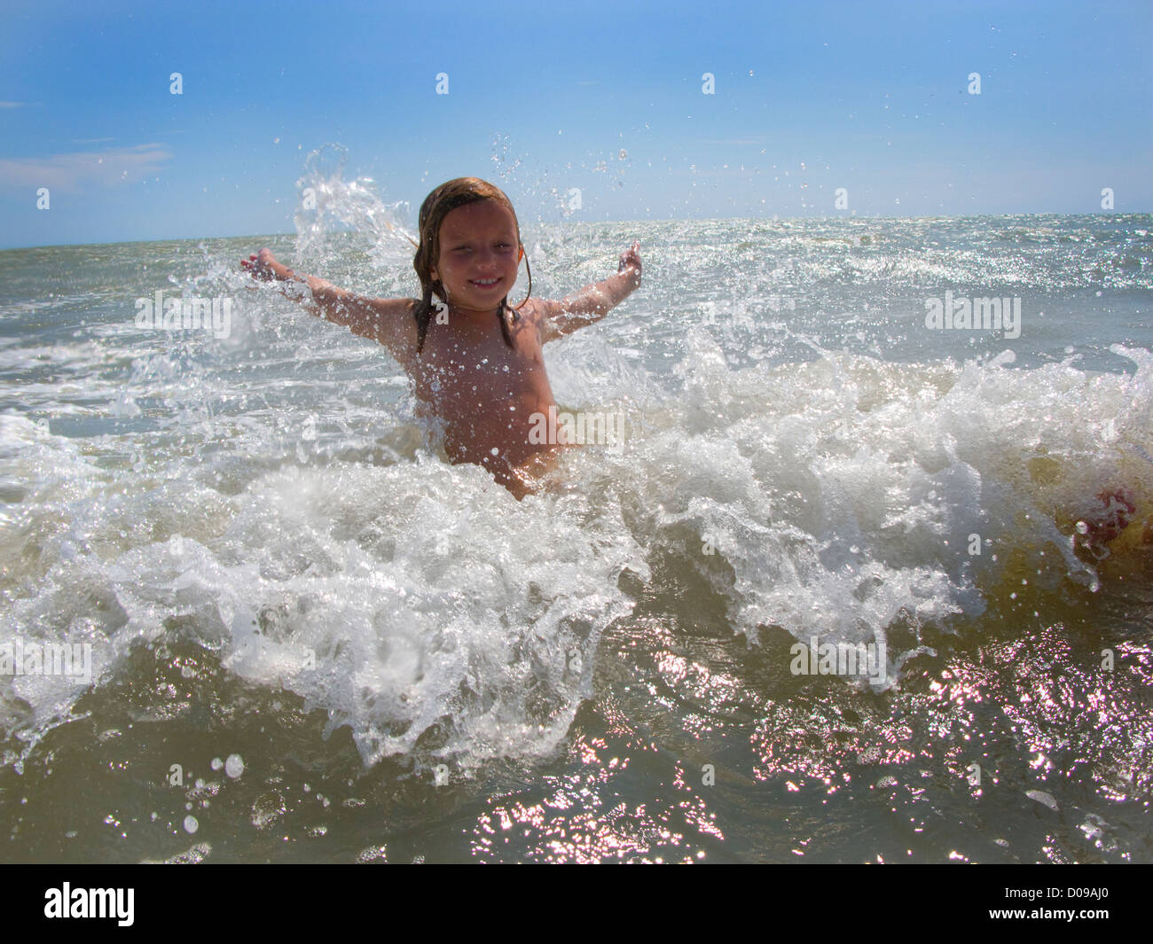 Bambino a nuotare in mare con onde che si infrangono contro di lei Foto Stock