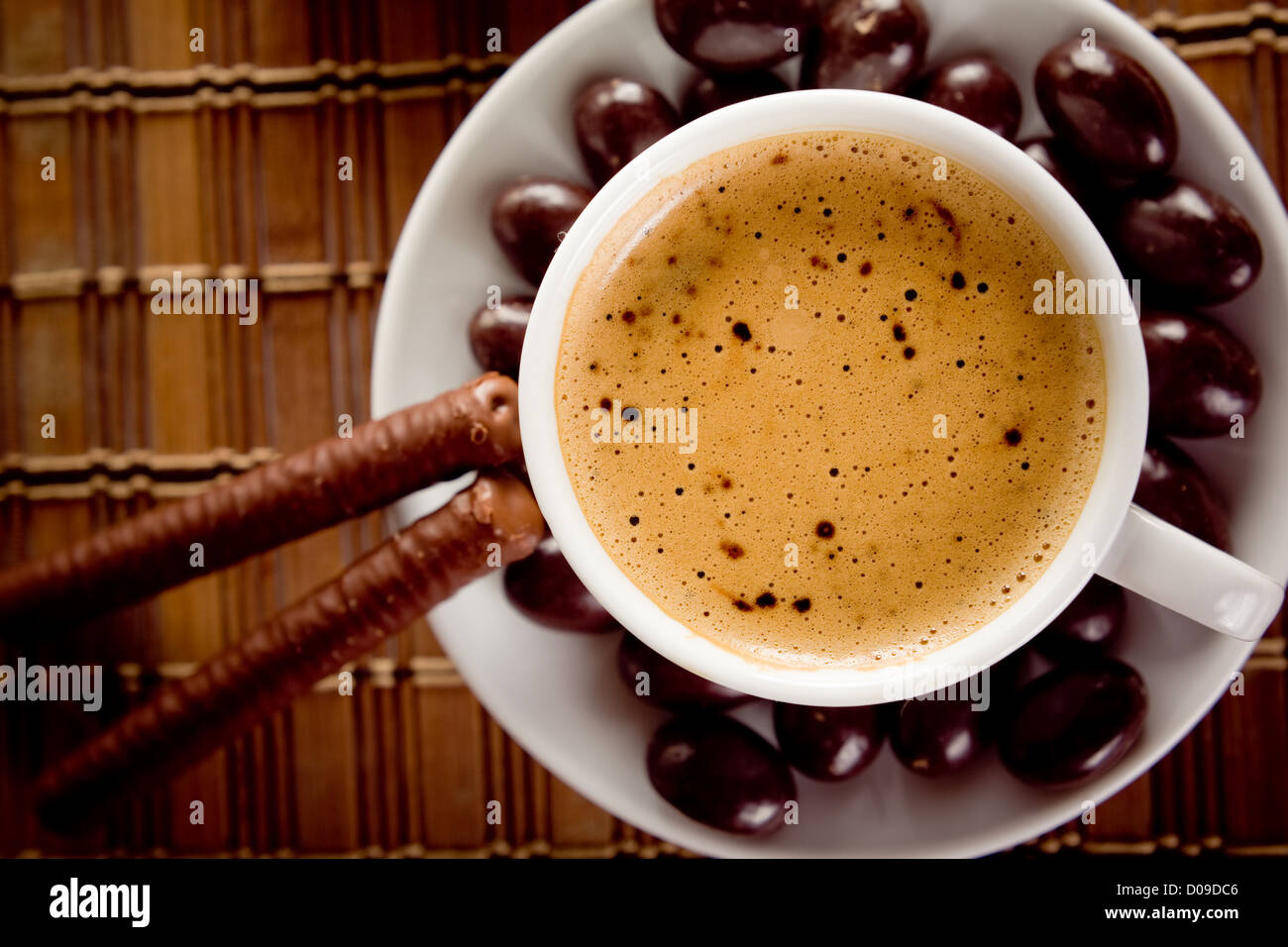 Tazza di caffè su una tabella con i dadi di cioccolato e bastoni Foto Stock