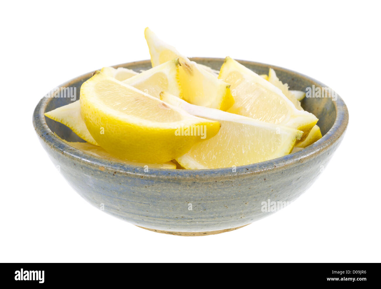 Un vecchio recipiente di ceramica riempito con spicchi di limone su uno sfondo bianco. Foto Stock