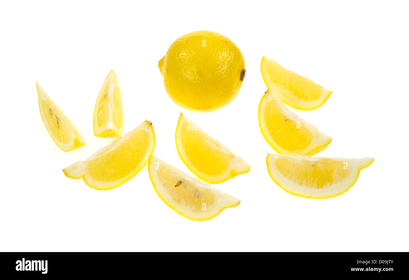 Un limone intero in background con diversi cunei in primo piano su uno sfondo bianco. Foto Stock