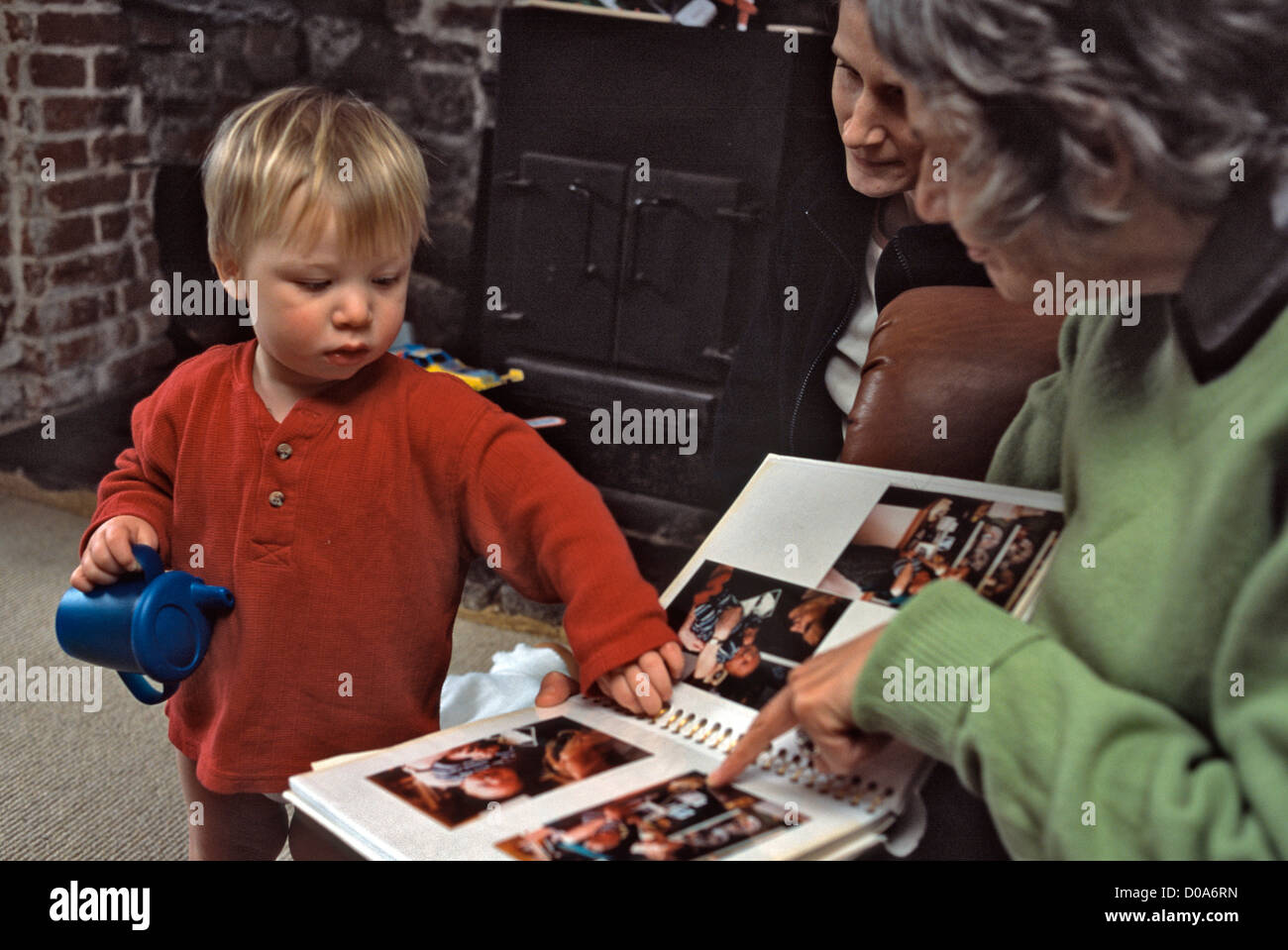2 anno vecchio ragazzo guardando le foto del bambino con la nonna e la madre Foto Stock