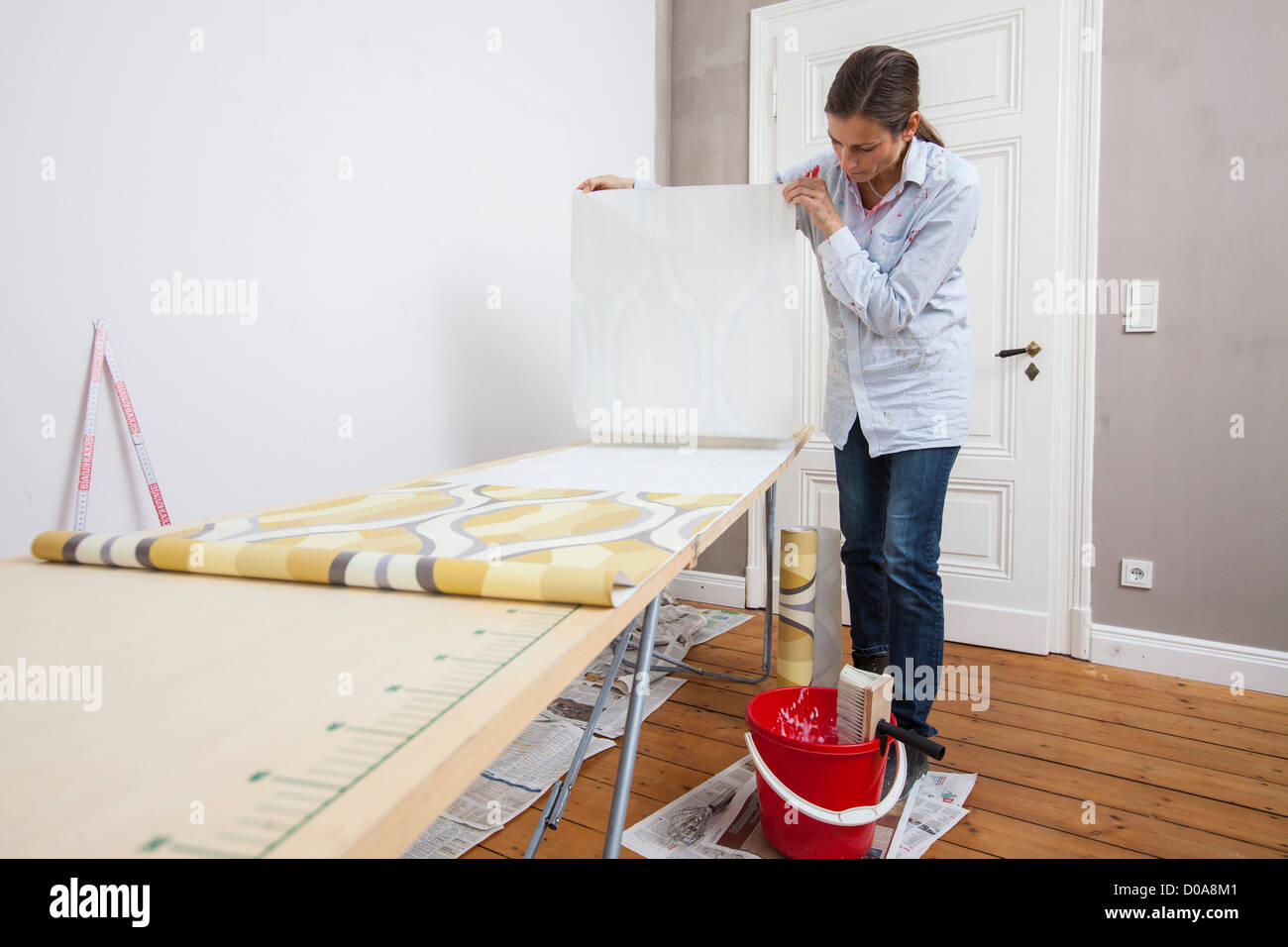 Giovane moglie sta rinnovando la sua casa. Paperhanging, nuovo sfondo. Fai da te. Foto Stock