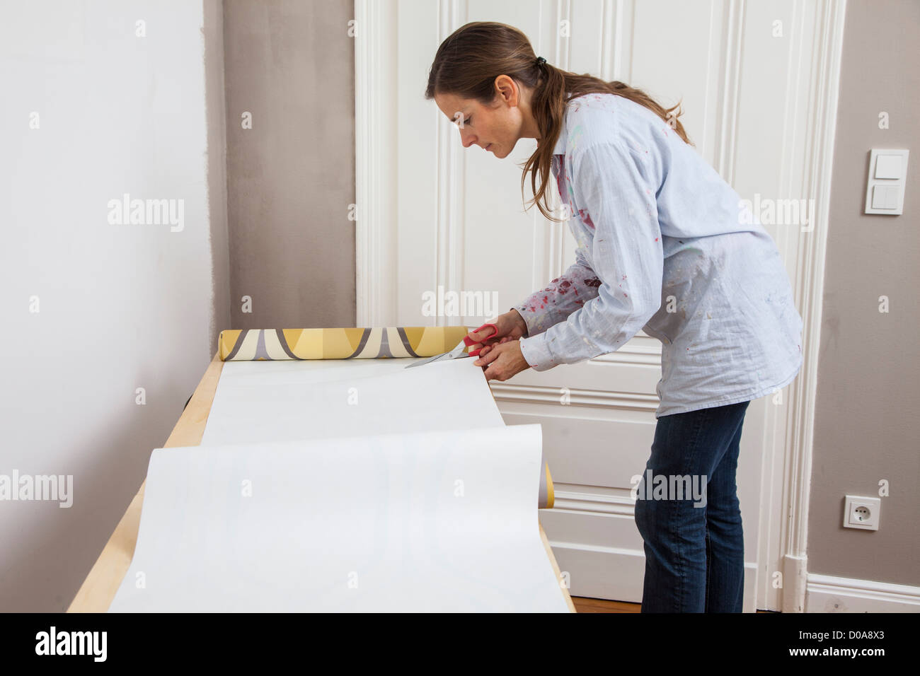 Giovane moglie sta rinnovando la sua casa. Paperhanging, nuovo sfondo. Fai da te. Foto Stock