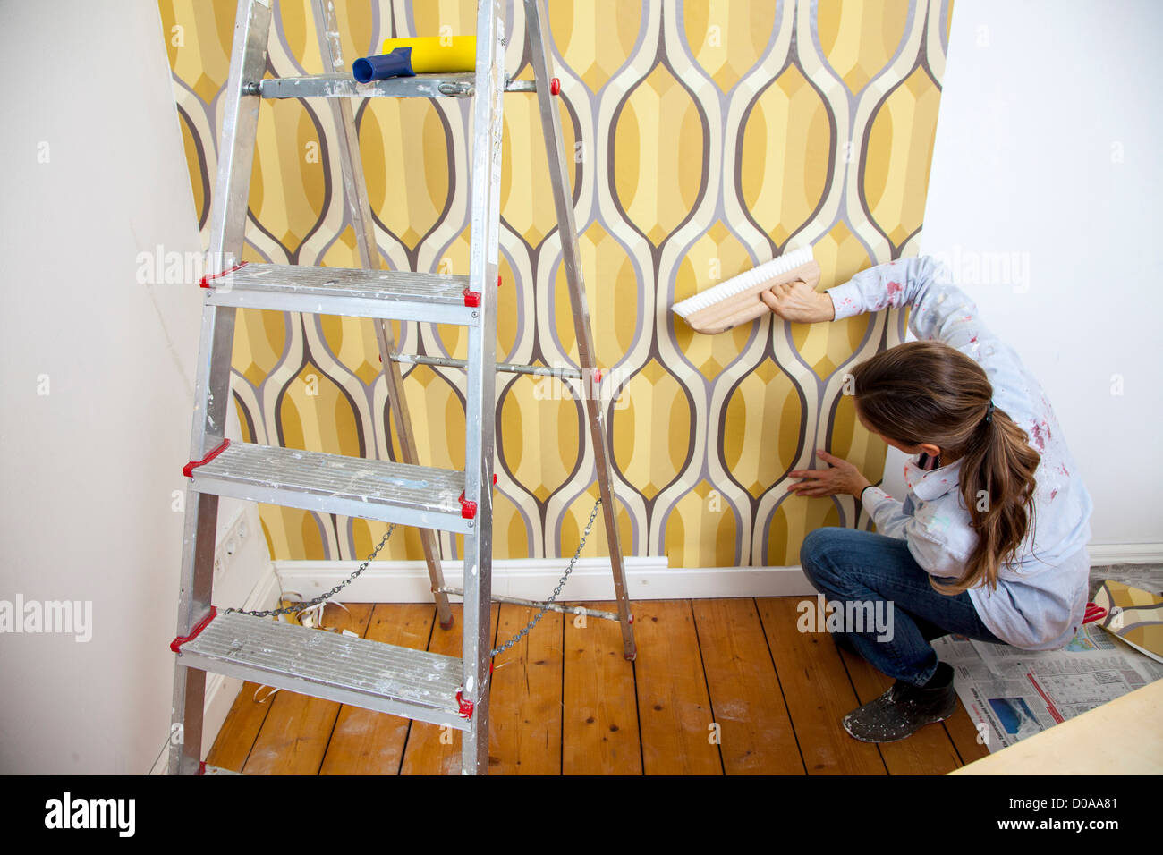 Giovane moglie sta rinnovando la sua casa. Paperhanging, nuovo sfondo. Fai da te. Foto Stock