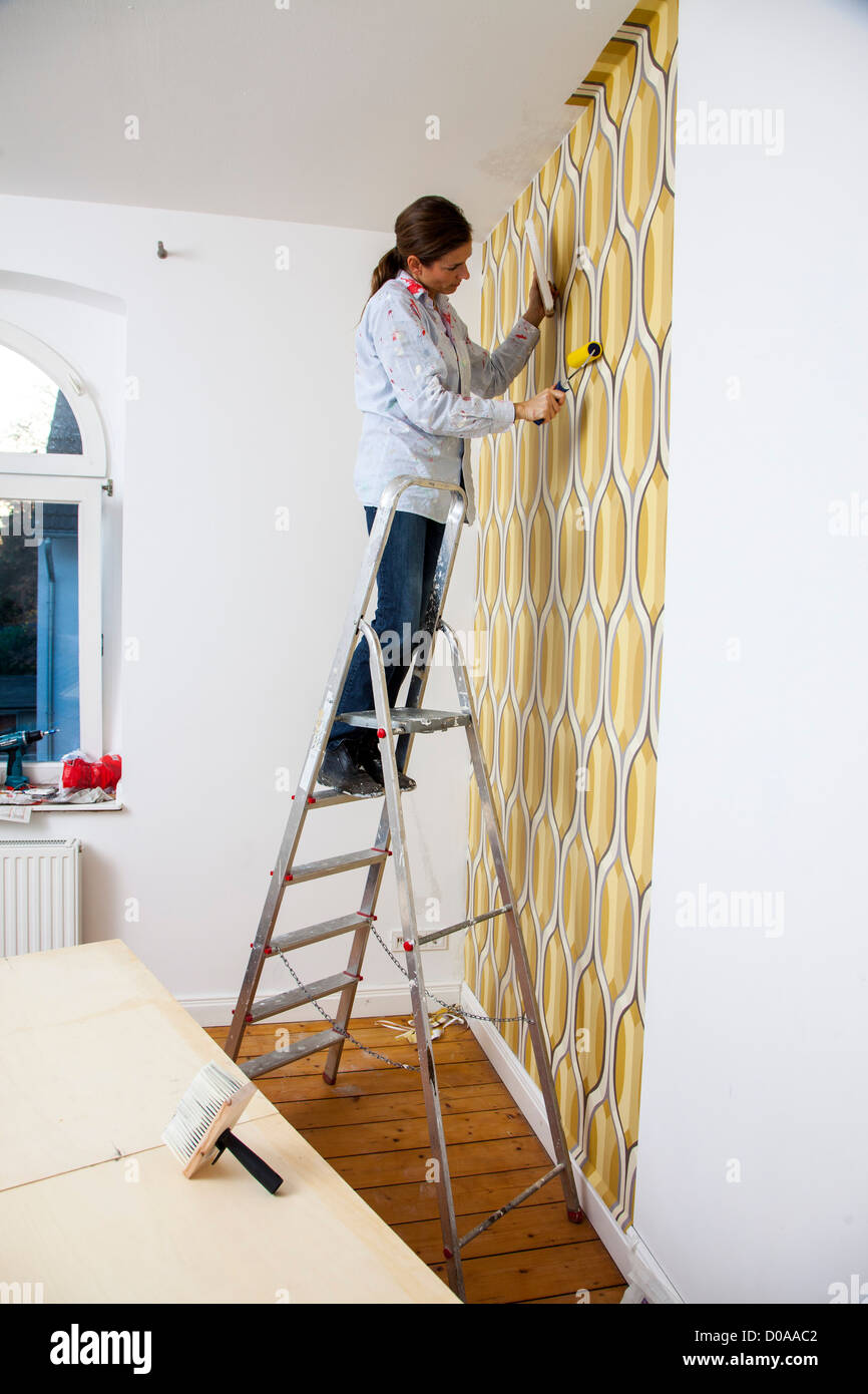 Giovane moglie sta rinnovando la sua casa. Paperhanging, nuovo sfondo. Fai da te. Foto Stock