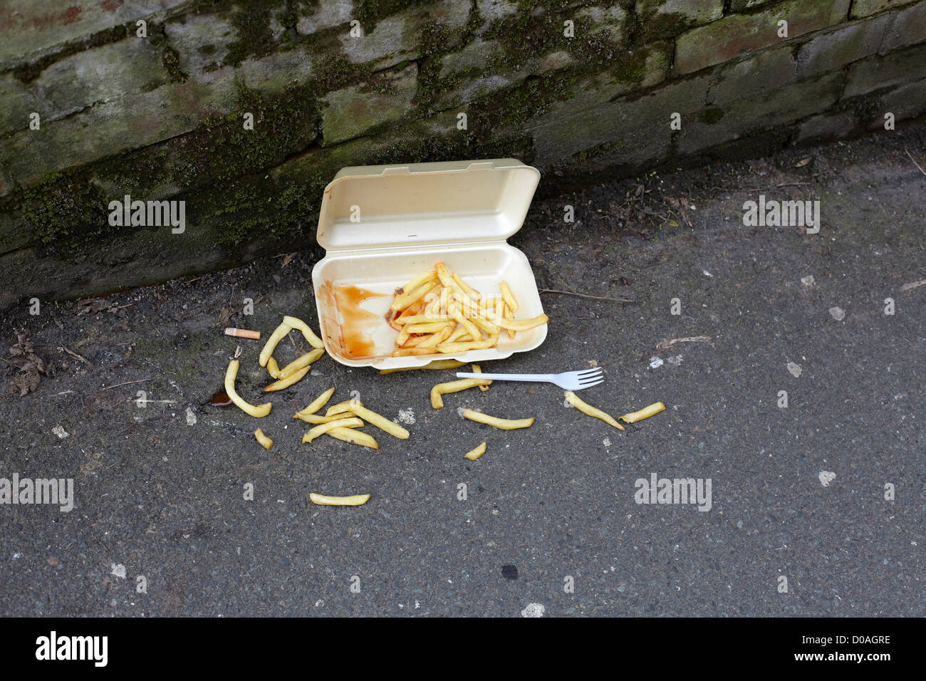 Chip e cartone da asporto gettati sul marciapiede con forcella di plastica, Lancaster, Regno Unito Foto Stock