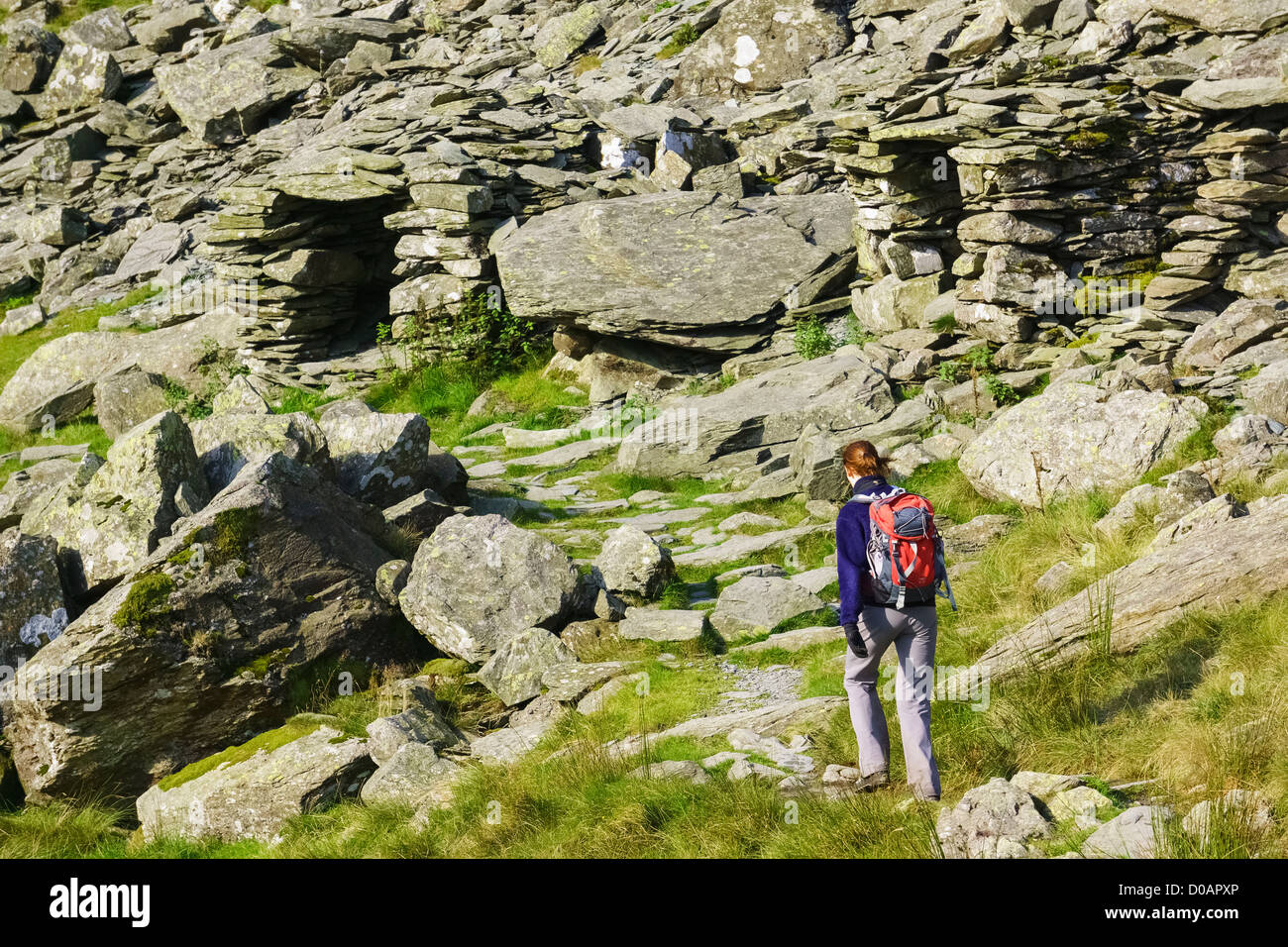 Una femmina di escursionista dirigendosi verso rifugi di pietra a piccolo acqua roccioso nel distretto del lago. Foto Stock