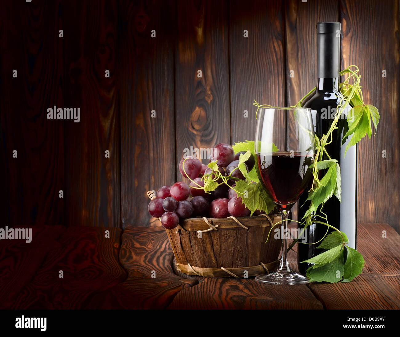 Vino rosso con un bicchiere di vino su sfondo di legno Foto Stock