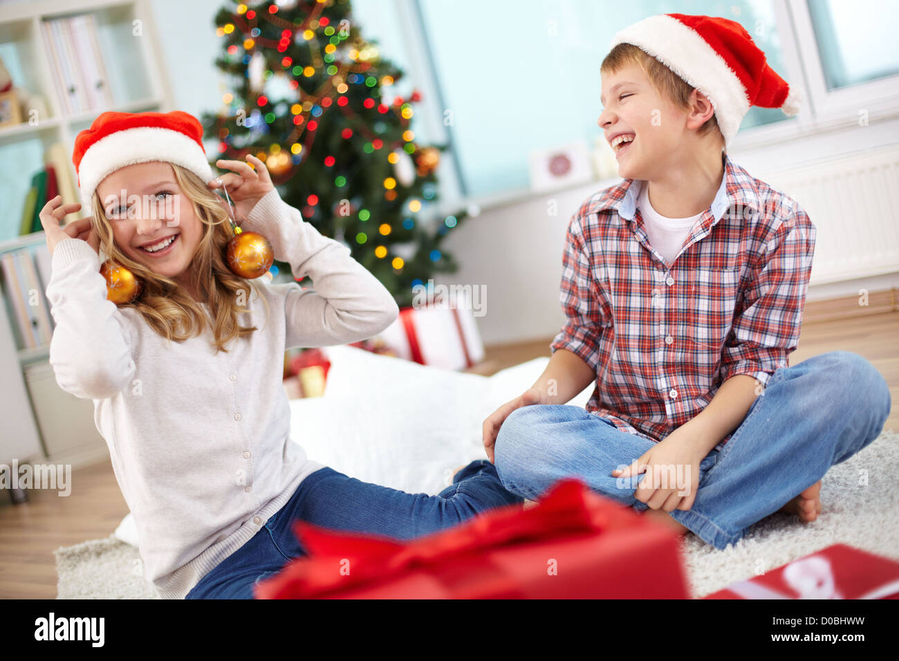 Ritratto di felice lad guardando la sua sorella cercando sul giocattolo decorativi sfere della sera di Natale Foto Stock