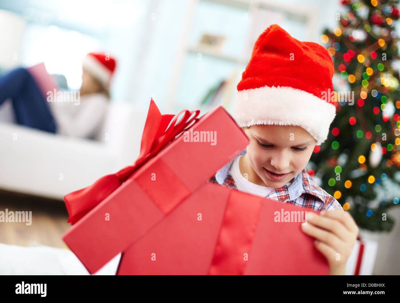 Ritratto di curioso ragazzo cerca all'interno di big red giftbox della sera di Natale Foto Stock