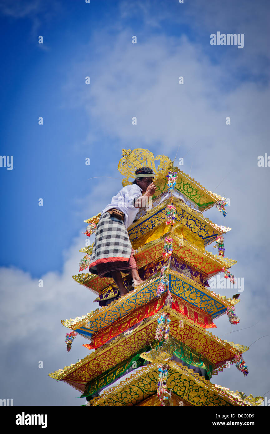 Una persona si arrampica la torre dove il defunto re di Ubud è in attesa di essere presi per la cremazione area con le offerte Foto Stock Una persona si arrampica la torre dove il defunto re di Ubud è in attesa di essere presi per la cremazione area con le offerte Foto Stock