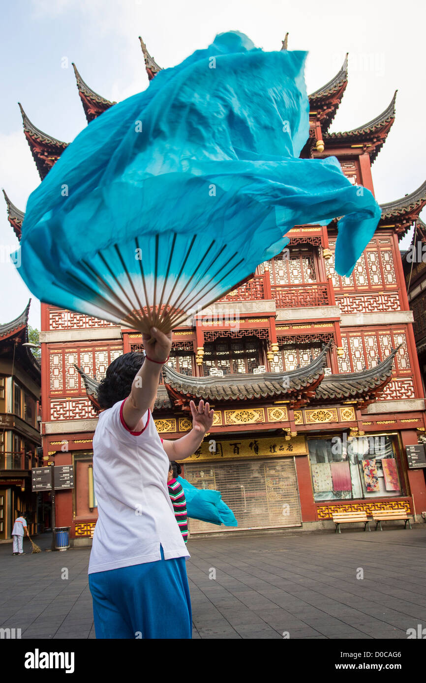 Una donna anziana esegue il cinese la danza della ventola per esercitare nella storica Yu Yuan Gardens Shanghai, Cina Foto Stock