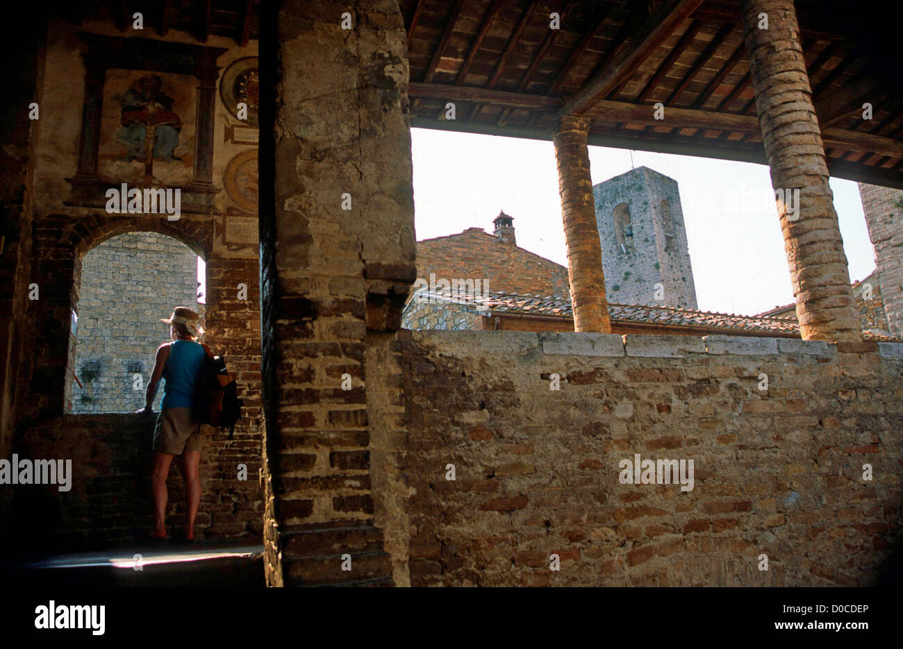 Un solitario visitatore esplora storica GIMIGNANO SIENA TOSCANA ITALIA SETTENTRIONALE Foto Stock