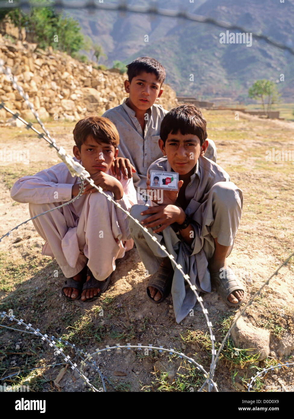 I bambini del villaggio di Nangalam sguardo attraverso il filo di concertina Foto Stock
