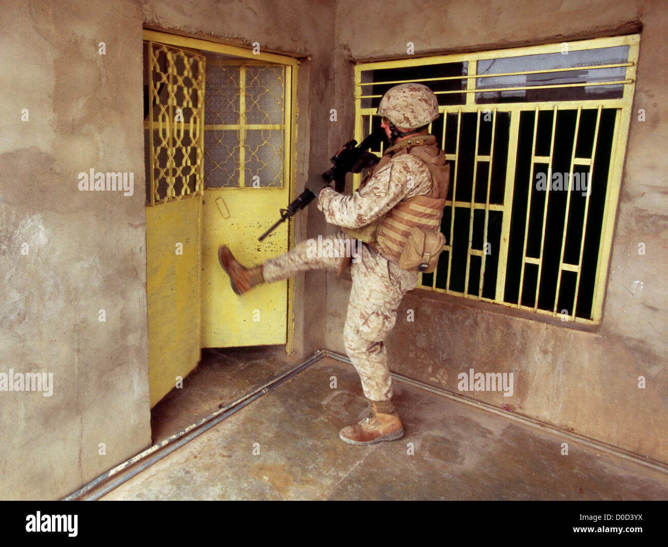 La calciata aprire una porta di un sospetto di Al Qaeda operatore a Haditha in Iraq Foto Stock
