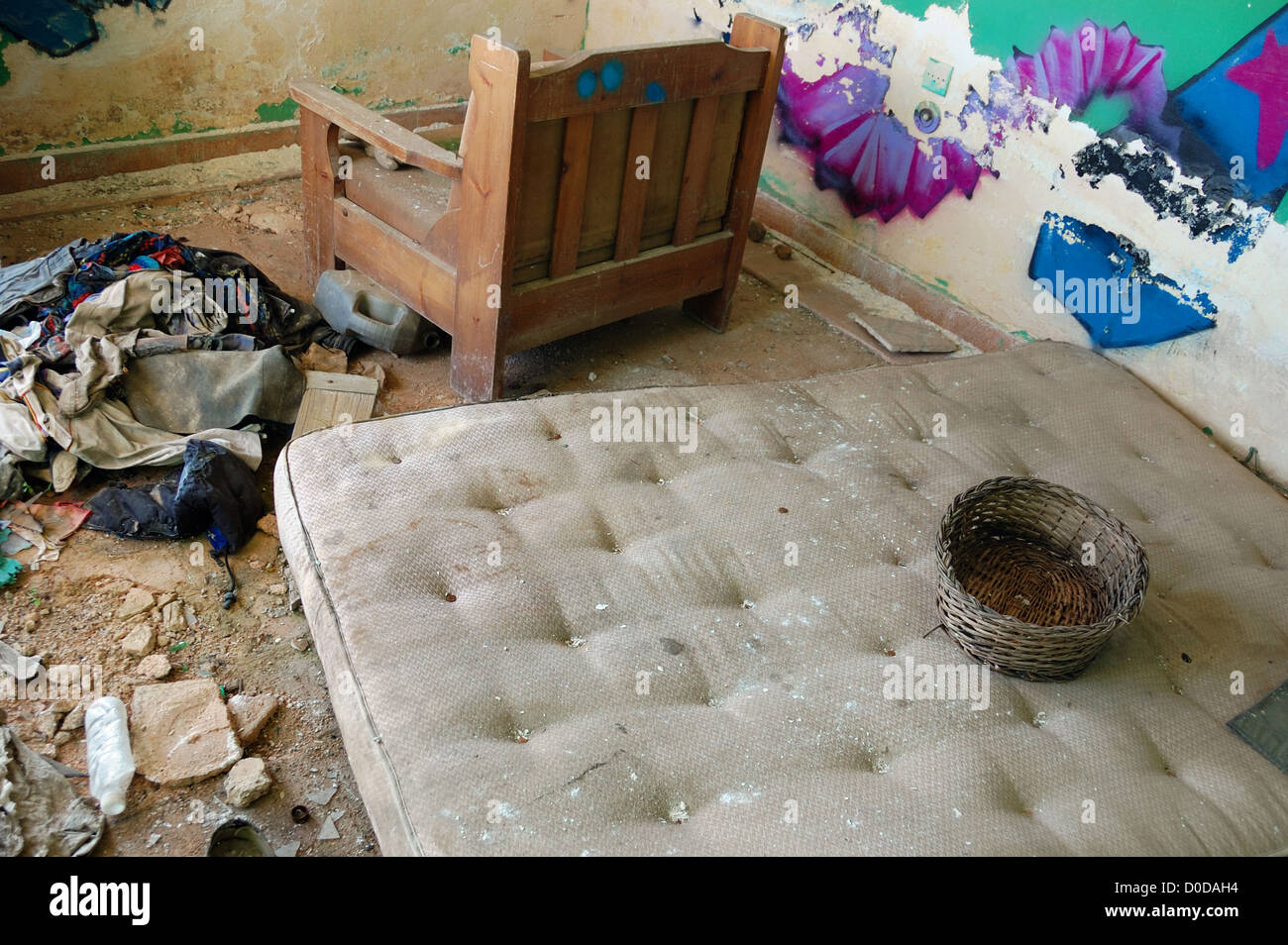 Materasso sporco e vestiti sul pavimento di una casa abbandonata. Foto Stock