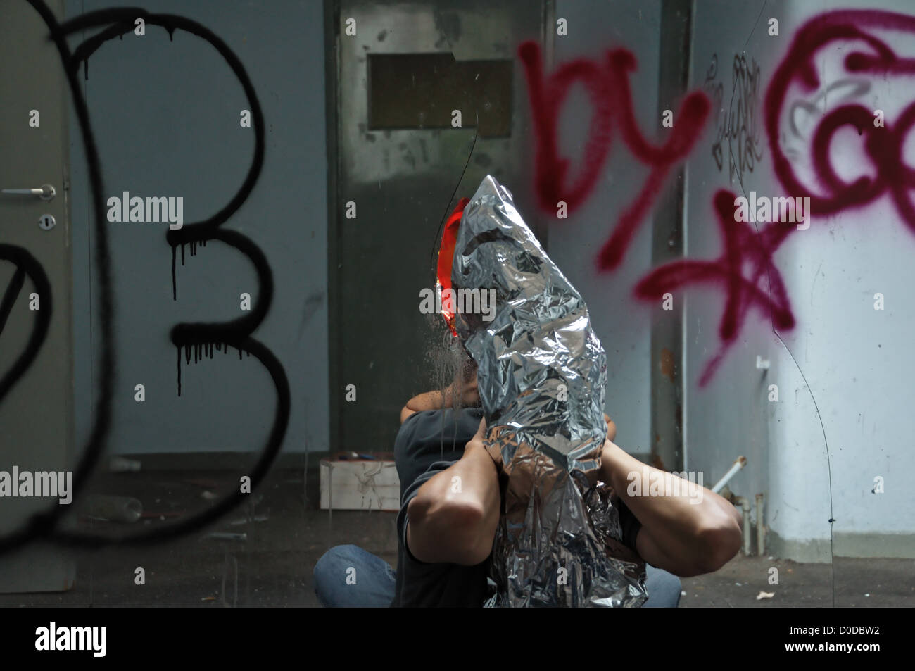 Distorto l'uomo che emerge attraverso il vetro rotto uno specchio in abbandonato interni. Foto Stock