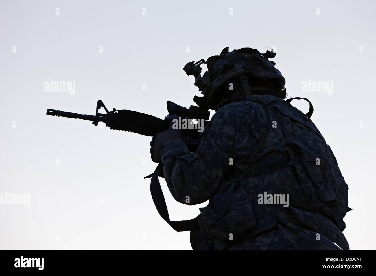 Stati Uniti Soldato dell'esercito puntando la sua arma di Sunrise Foto Stock