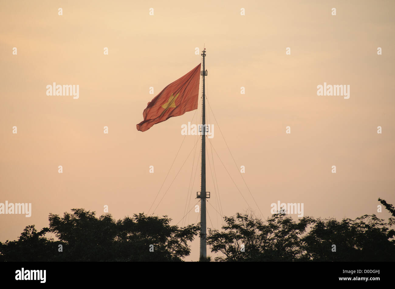 Bandiera vietnamita Imperial City Hue Vietnam // HUE, Vietnam — la bandiera vietnamita nella foschia, che sventola sulla cittadella della città imperiale di Hue, Vietnam. Un palazzo auto-chiuso e fortificato, il complesso comprende la città Proibita viola, che era il santuario interno della casa imperiale, nonché templi, cortili, giardini e altri edifici. Gran parte della città imperiale fu danneggiata o distrutta durante la guerra del Vietnam. È ora dichiarato patrimonio dell'umanità dell'UNESCO. Foto Stock