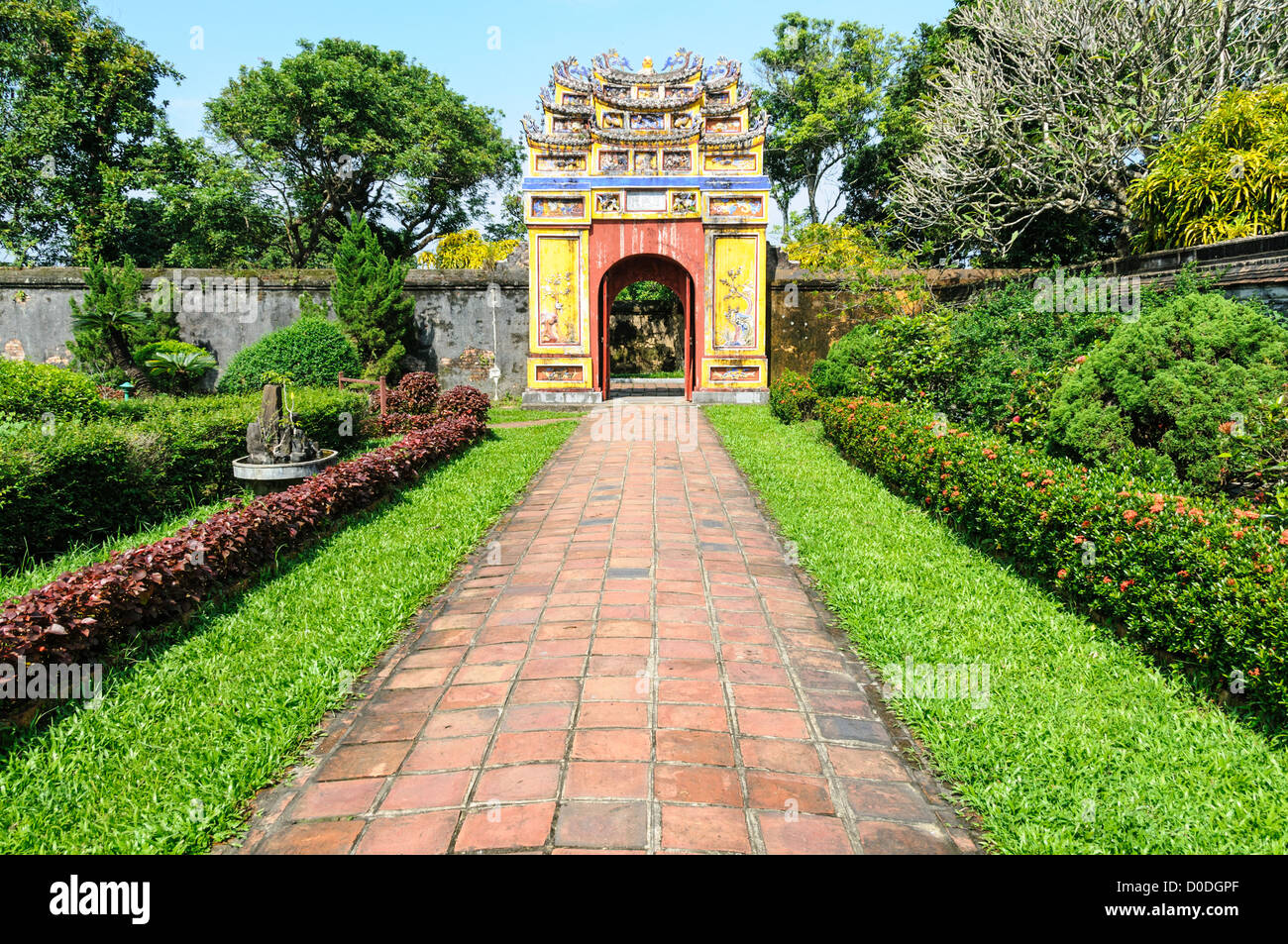 Imperial City Garden Path Hue Vietnam // HUE, Vietnam — Un giardino che fa la terra della città imperiale di Hue, Vietnam. Un palazzo auto-chiuso e fortificato, il complesso comprende la città Proibita viola, che era il santuario interno della casa imperiale, nonché templi, cortili, giardini e altri edifici. Gran parte della città imperiale fu danneggiata o distrutta durante la guerra del Vietnam. È ora dichiarato patrimonio dell'umanità dell'UNESCO. Foto Stock