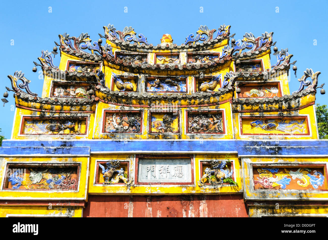 Imperial City Courtyard Gate Decorations Hue Vietnam // HUE, Vietnam — decorazioni ornate sulla parte superiore di un cancello del cortile presso la città imperiale di Hue, Vietnam. Un palazzo auto-chiuso e fortificato, il complesso comprende la città Proibita viola, che era il santuario interno della casa imperiale, nonché templi, cortili, giardini e altri edifici. Gran parte della città imperiale fu danneggiata o distrutta durante la guerra del Vietnam. È ora dichiarato patrimonio dell'umanità dell'UNESCO. Foto Stock