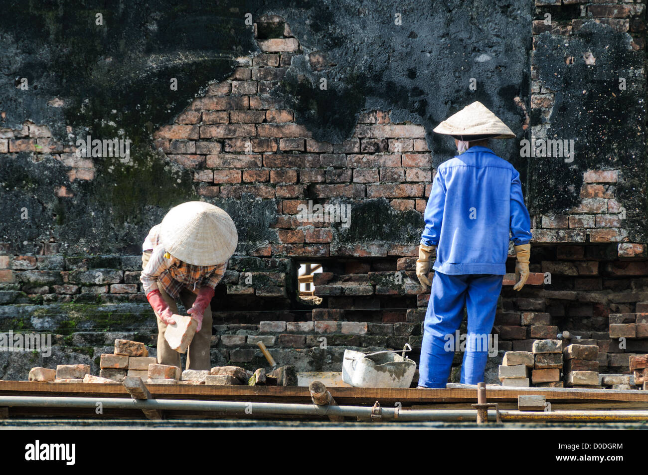 Imperial City Wall Renovation Hue Vietnam // HUE, Vietnam - i lavoratori ristrutturano un muro danneggiato nella città imperiale di Hue, Vietnam. Un palazzo auto-chiuso e fortificato, il complesso comprende la città Proibita viola, che era il santuario interno della casa imperiale, nonché templi, cortili, giardini e altri edifici. Gran parte della città imperiale fu danneggiata o distrutta durante la guerra del Vietnam. È ora dichiarato patrimonio dell'umanità dell'UNESCO. Foto Stock