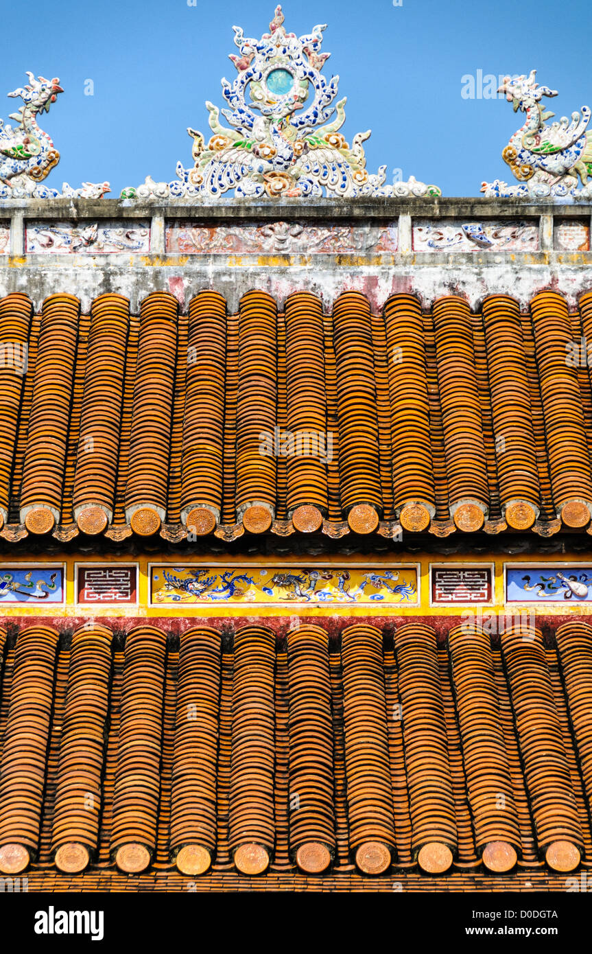 Imperial City Decorated Roof Hue Vietnam // HUE, Vietnam — Un tetto decorato in un edificio restaurato nella città imperiale di Hue, Vietnam. Un palazzo auto-chiuso e fortificato, il complesso comprende la città Proibita viola, che era il santuario interno della casa imperiale, nonché templi, cortili, giardini e altri edifici. Gran parte della città imperiale fu danneggiata o distrutta durante la guerra del Vietnam. È ora dichiarato patrimonio dell'umanità dell'UNESCO. Foto Stock
