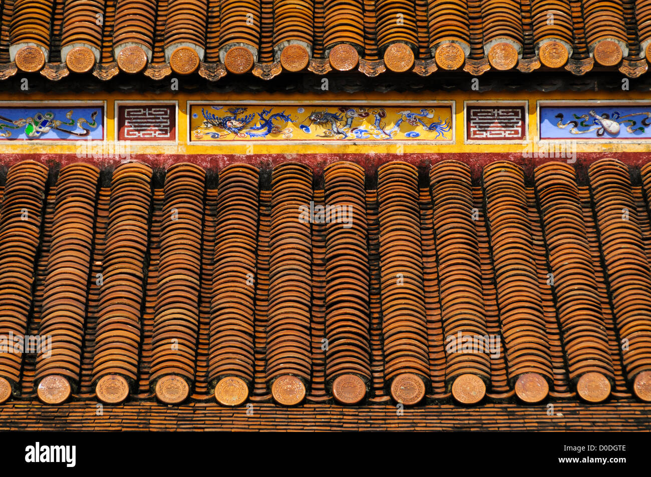 Piastrelle e dipinti del tetto della città Imperiale Hue Vietnam // HUE, Vietnam - piastrelle del tetto impilate con cura e dipinti ornati sul tetto di un edificio restaurato nella città Imperiale di Hue, Vietnam. Un palazzo auto-chiuso e fortificato, il complesso comprende la città Proibita viola, che era il santuario interno della casa imperiale, nonché templi, cortili, giardini e altri edifici. Gran parte della città imperiale fu danneggiata o distrutta durante la guerra del Vietnam. È ora dichiarato patrimonio dell'umanità dell'UNESCO. Foto Stock