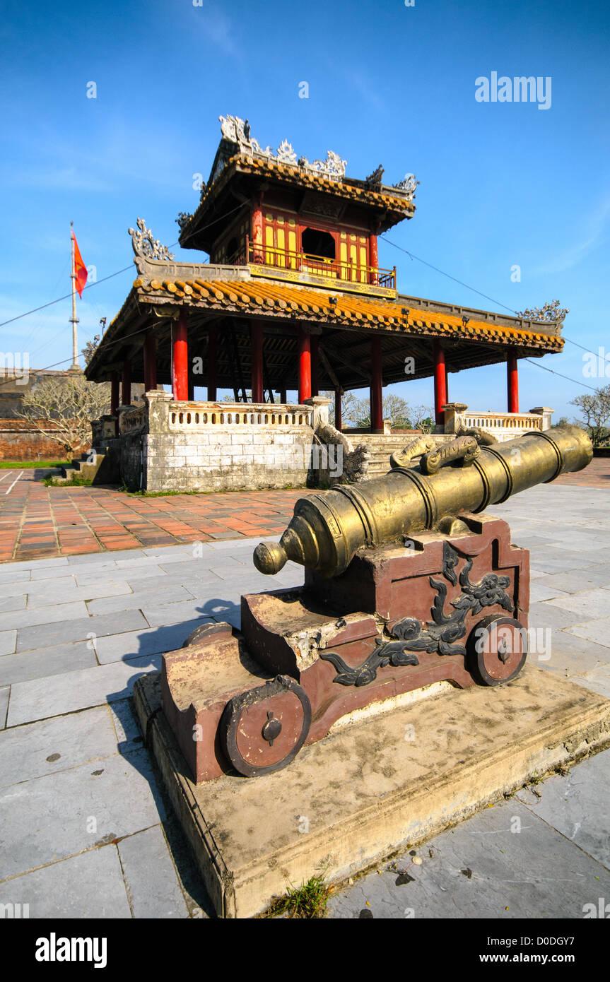 Imperial City Pagoda e Cannon Hue Vietnam // HUE, Vietnam — Una pagoda restaurata e cannone nella città imperiale di Hue, Vietnam. Un palazzo auto-chiuso e fortificato, il complesso comprende la città Proibita viola, che era il santuario interno della casa imperiale, nonché templi, cortili, giardini e altri edifici. Gran parte della città imperiale fu danneggiata o distrutta durante la guerra del Vietnam. È ora dichiarato patrimonio dell'umanità dell'UNESCO. Foto Stock