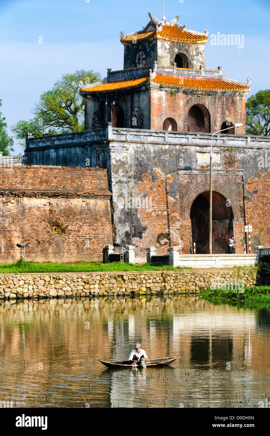 Imperial City Moat Fisherman Hue Vietnam // HUE, Vietnam — Un uomo pesca nelle acque del fossato che circonda la città imperiale di Hue, Vietnam. Un palazzo auto-chiuso e fortificato, il complesso comprende la città Proibita viola, che era il santuario interno della casa imperiale, nonché templi, cortili, giardini e altri edifici. Gran parte della città imperiale fu danneggiata o distrutta durante la guerra del Vietnam. È ora dichiarato patrimonio dell'umanità dell'UNESCO. Foto Stock