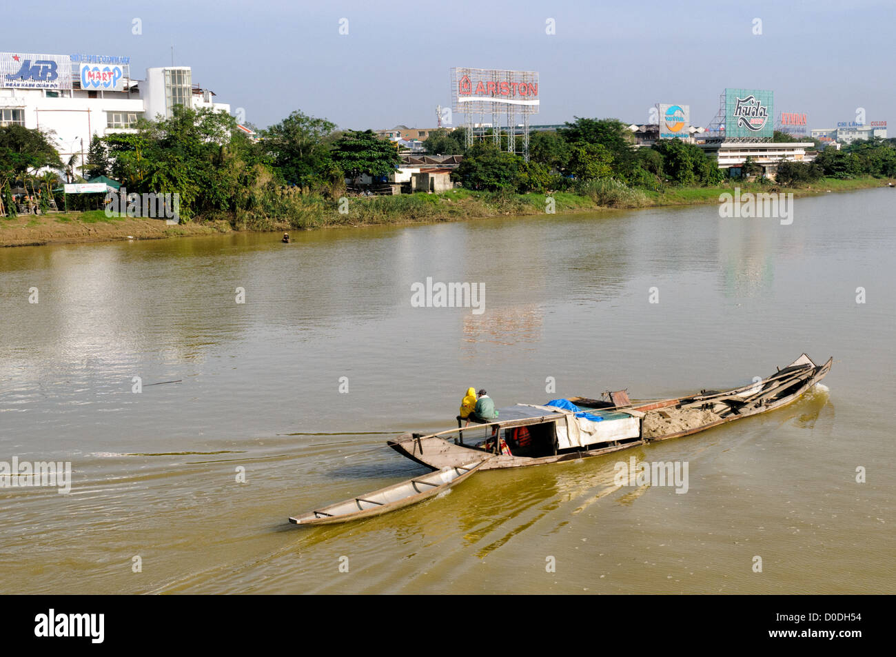 Sampan che trasporta il suolo fiume profumo Hue Vietnam // HUE, Vietnam — Un sampan di legno che trasporta terreno dragato si fa strada fino alle acque marroni del fiume profumo a Hue, Vietnam. Foto Stock