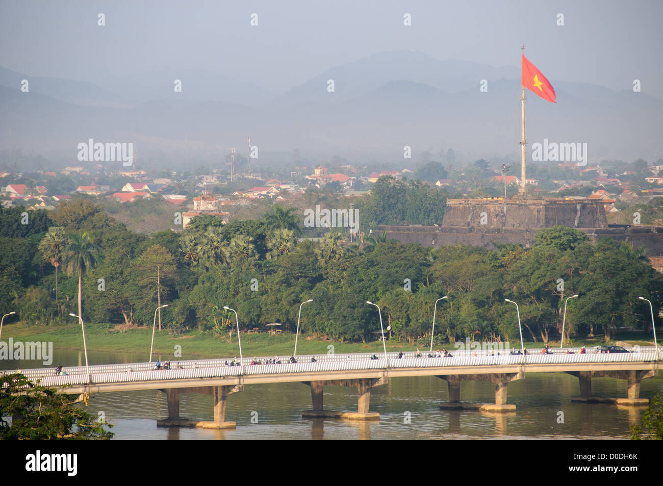 Imperial City Vietnamita Flag Hue Vietnam // HUE, Vietnam — la bandiera vietnamita sulle torri della cittadella della città imperiale sopra la città di Hue, con un ponte sul fiume dei profumi in primo piano. Foto Stock