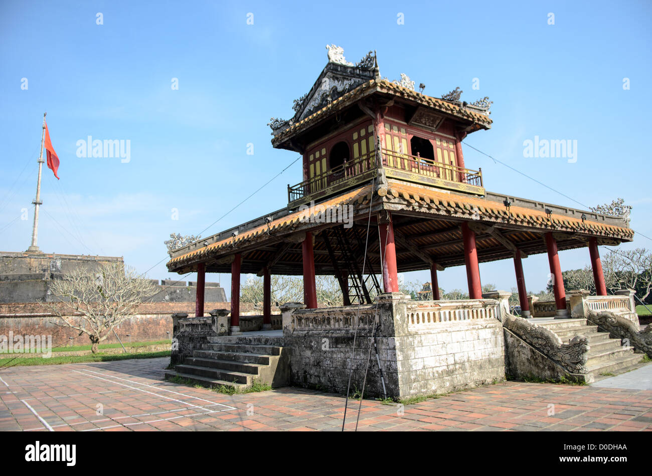 Imperial City Pagoda Hue Vietnam // HUE, Vietnam — Una pagoda sul fossato della città imperiale di Hue, Vietnam. Un palazzo auto-chiuso e fortificato, il complesso comprende la città Proibita viola, che era il santuario interno della casa imperiale, nonché templi, cortili, giardini e altri edifici. Gran parte della città imperiale fu danneggiata o distrutta durante la guerra del Vietnam. È ora dichiarato patrimonio dell'umanità dell'UNESCO. La cittadella, con la sua grande bandiera vietnamita, si trova a sinistra della cornice sullo sfondo. Foto Stock