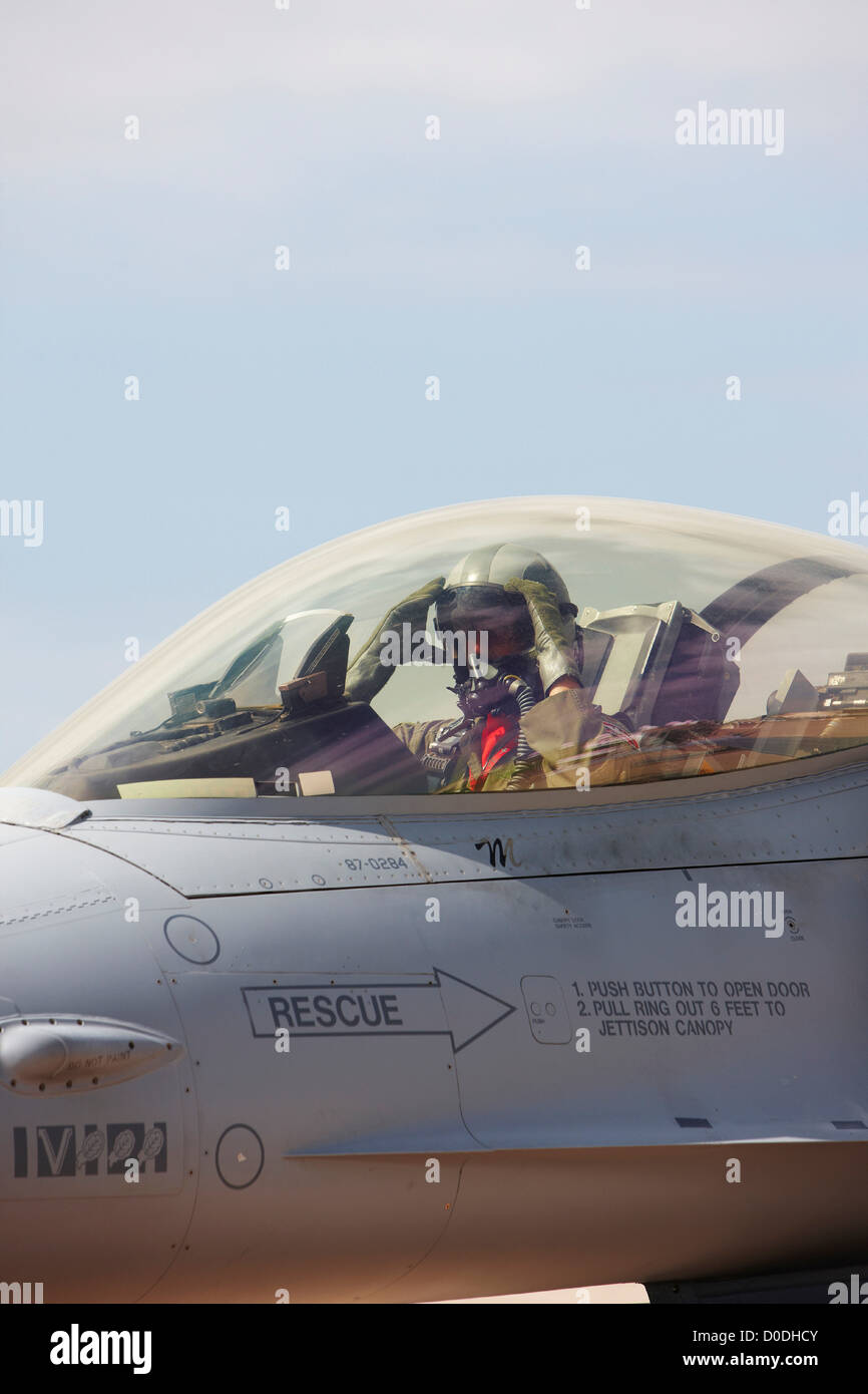 Pilota di caccia nella cabina di pilotaggio di F-16, regolazione della visiera del casco Foto Stock