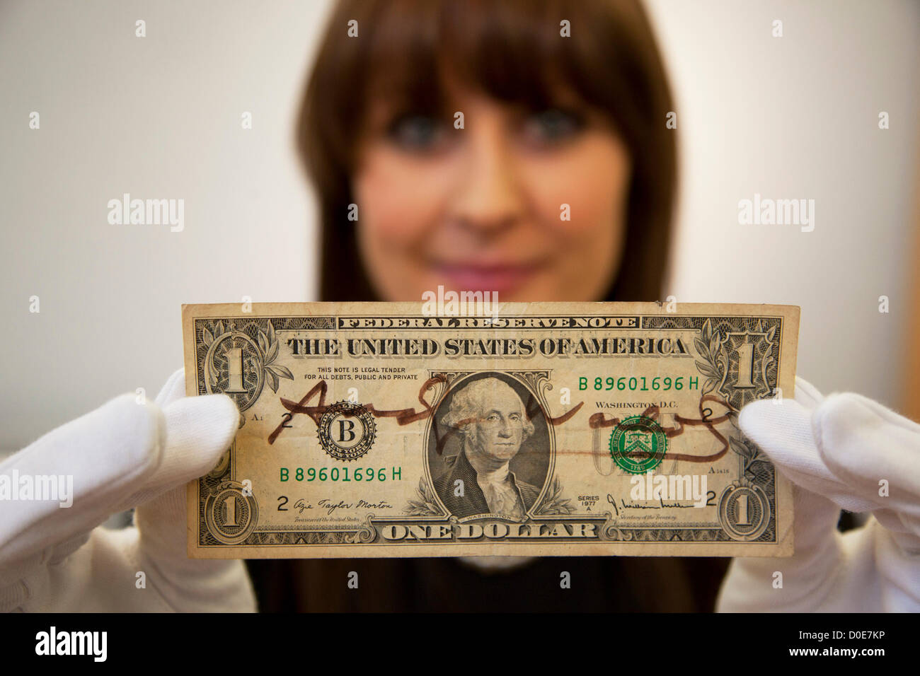 Londra, Regno Unito. Venerdì 23 novembre 2012. Christies auction house presentazione di memorabilia provenienti da ogni decennio del secolo passato della cultura popolare da industrie di film e musica. Christie's Specialista Caitlin Graham mostra un dollaro firmata da Andy Warhol. Foto Stock