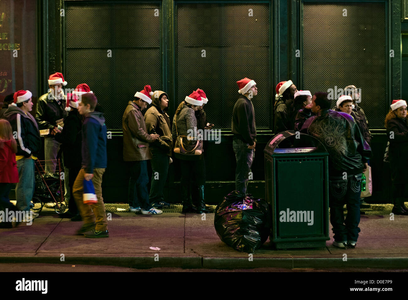 Novembre 22, 2012, New York, NY. Persone che indossano Santa Claus cappelli supporto in linea per prendere vantaggio di vendita vacanza al Times Square Toys R Us store, che apre alle 8 del pomeriggio del Giorno del Ringraziamento vacanza. La linea era uno-e-un-metà blocchi lunghi. Foto Stock