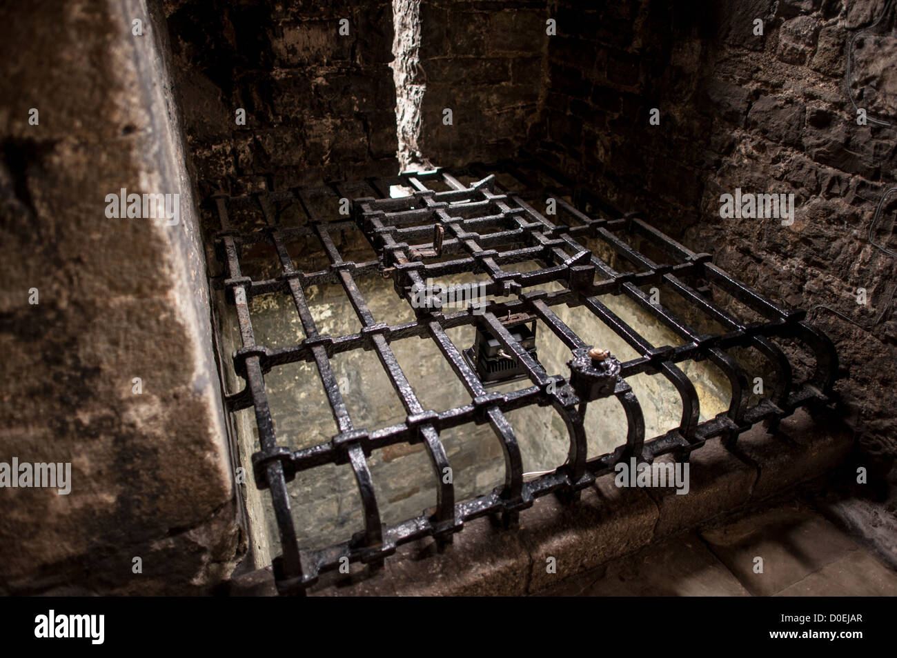 CAERNARFON, Galles: Una griglia in metallo nero copre il pozzo d'acqua originale al castello di Caernarfon nel Galles nord-occidentale. Un castello originariamente sorgeva sul sito risalente alla fine dell'XI secolo, ma alla fine del XIII secolo re Edoardo i commissionò una nuova struttura che si erge fino ad oggi. Ha torri caratteristiche ed è uno dei castelli meglio conservati della serie commissionata da Edoardo I. Foto Stock