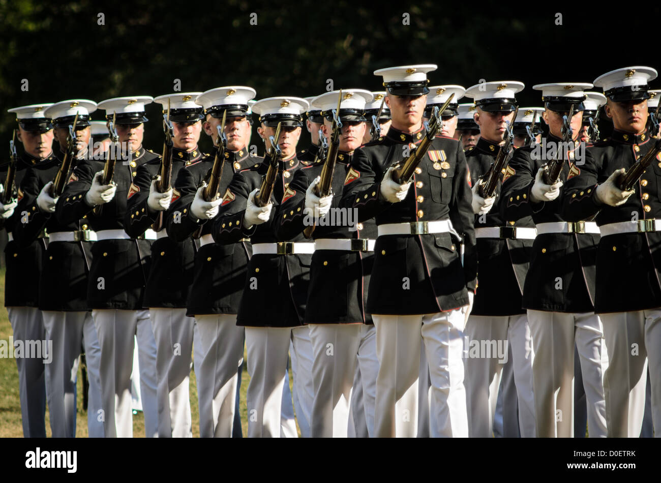 ARLINGTON, Virginia, Stati Uniti - il Marine Corps Silent Drill Platoon si esibisce durante la Sunset Parade al Marine Corps War Memorial, noto anche come Iwo Jima Memorial, ad Arlington, Virginia. La Sunset Parade, caratterizzata da movimenti di precisione e musica, si svolge il martedì sera durante i mesi estivi. L'iconico memoriale, raffigurante la bandiera che innalza su Iwo Jima, funge da sfondo drammatico per questa antica tradizione militare. Foto Stock