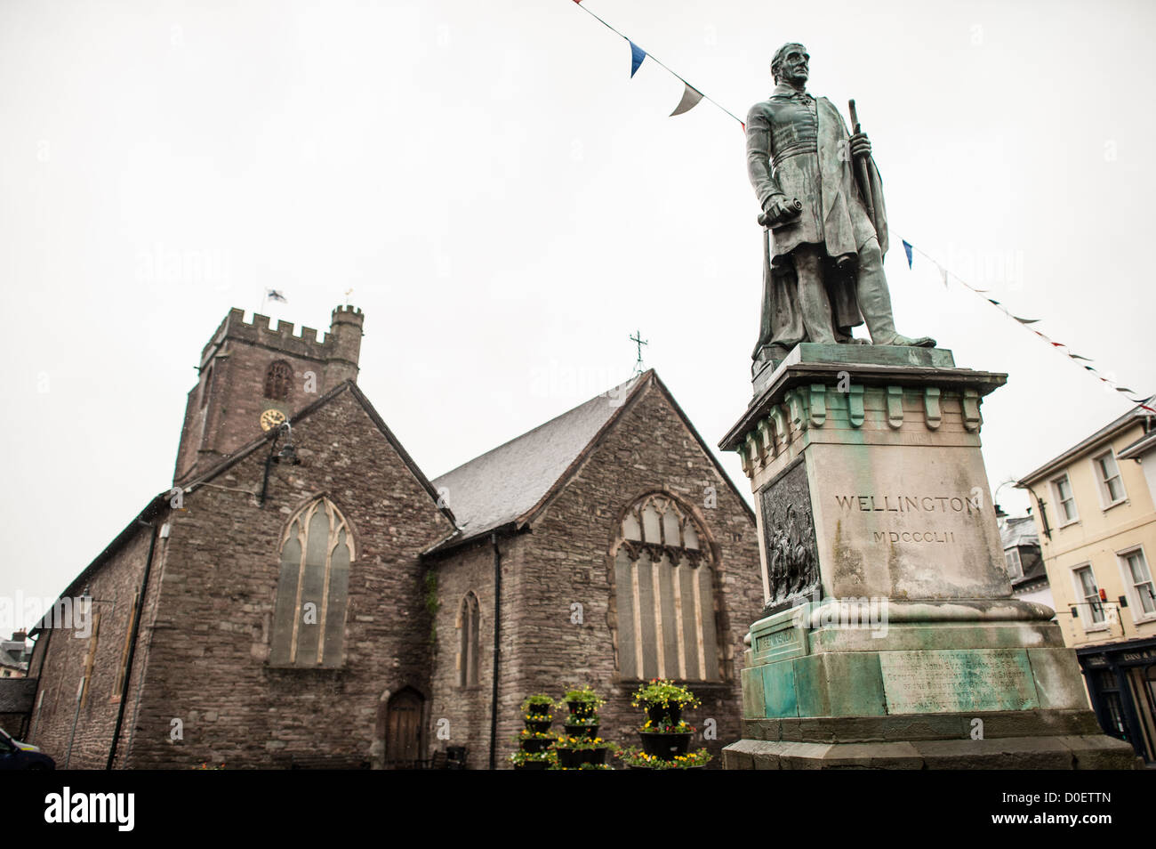 BRECON, Galles — Una statua di Arthur Wellesley, i duca di Wellington, si erge sotto la pioggia di fronte alla chiesa parrocchiale di St Mary a Brecon. Il monumento in pietra onora il comandante militare e statista britannico meglio noto per aver sconfitto Napoleone nella battaglia di Waterloo nel 1815. La chiesa di Santa Maria, con la sua caratteristica architettura medievale, è stata un luogo di culto per oltre 900 anni e divenne cattedrale di Brecon nel 1923, funzionando come sede del vescovo di Swansea e Brecon all'interno della Chiesa in Galles. Foto Stock