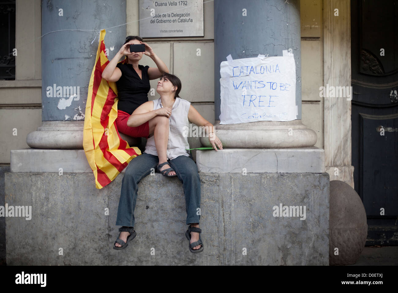 Due giovani donne con una bandiera catalana di scattare una foto con un cellulare durante il catalano della giornata nazionale marzo a Barcellona Foto Stock