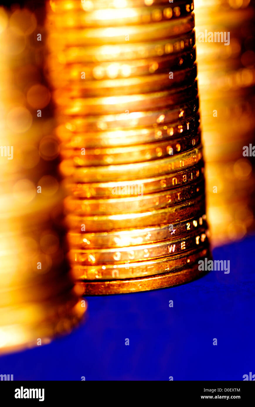 Diverse pile di monete d'oro su sfondo blu Foto Stock