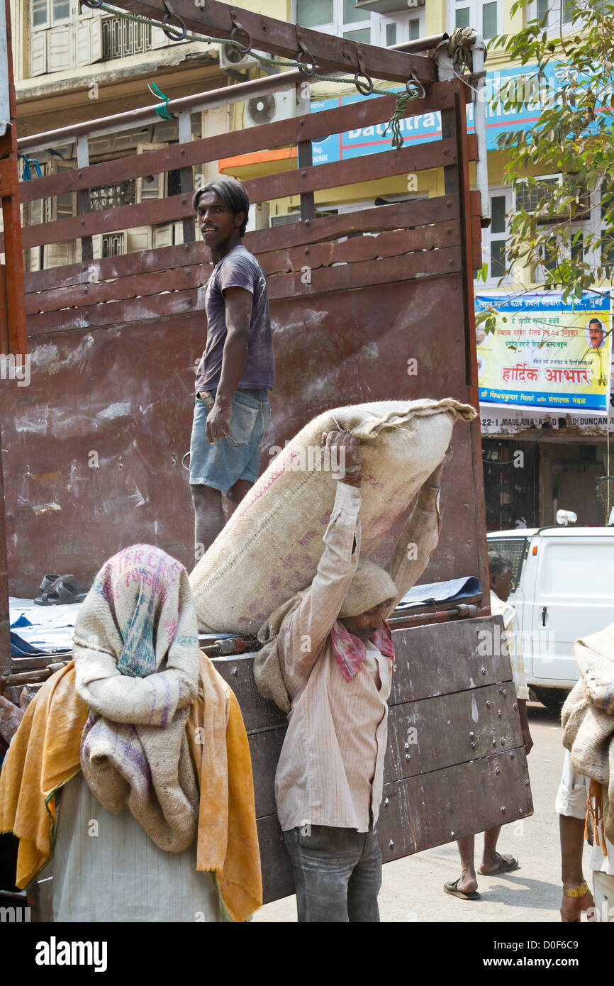 I lavoratori lo scarico di un carrello con sacchi di cemento in Mumbai, India Foto Stock